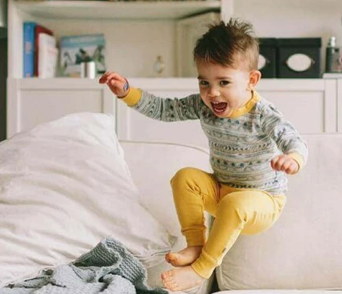 Happy little boy jumping on a bed.